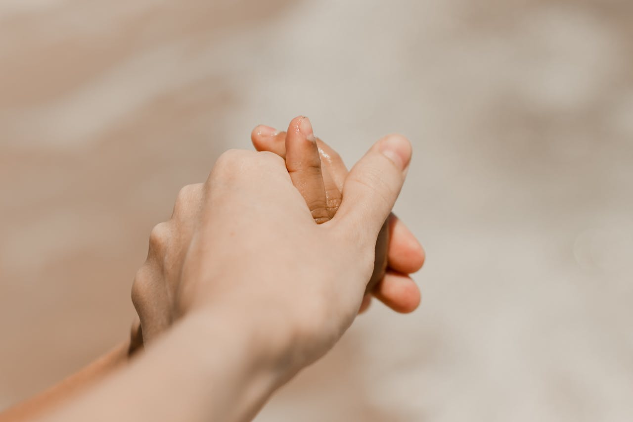Close-up of adults holding childs hand on a beach in Aracati, Brazil.